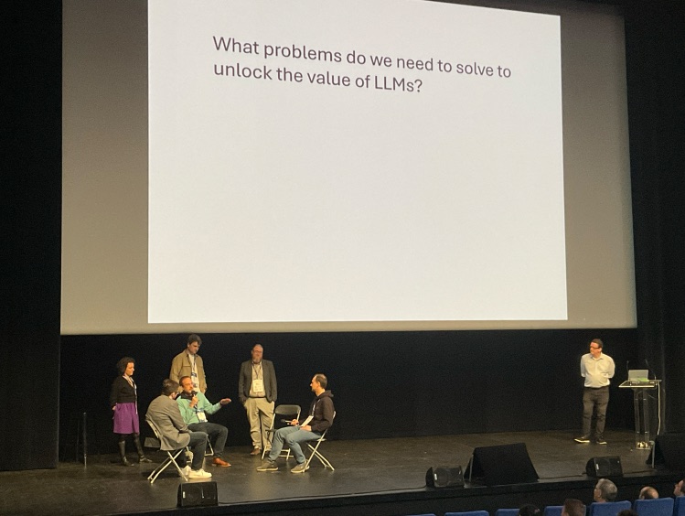 Chris Matts on stage with a slide asking, "What problems do we need to solve to unlock the value of LLMs?"